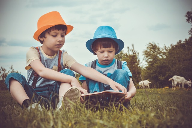 due bambini che leggono un libro sul prato all'aria aperta